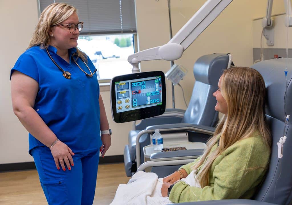 Nurse talking with a patient seated in an infusion chair during treatment at Gadsden Cancer Clinic