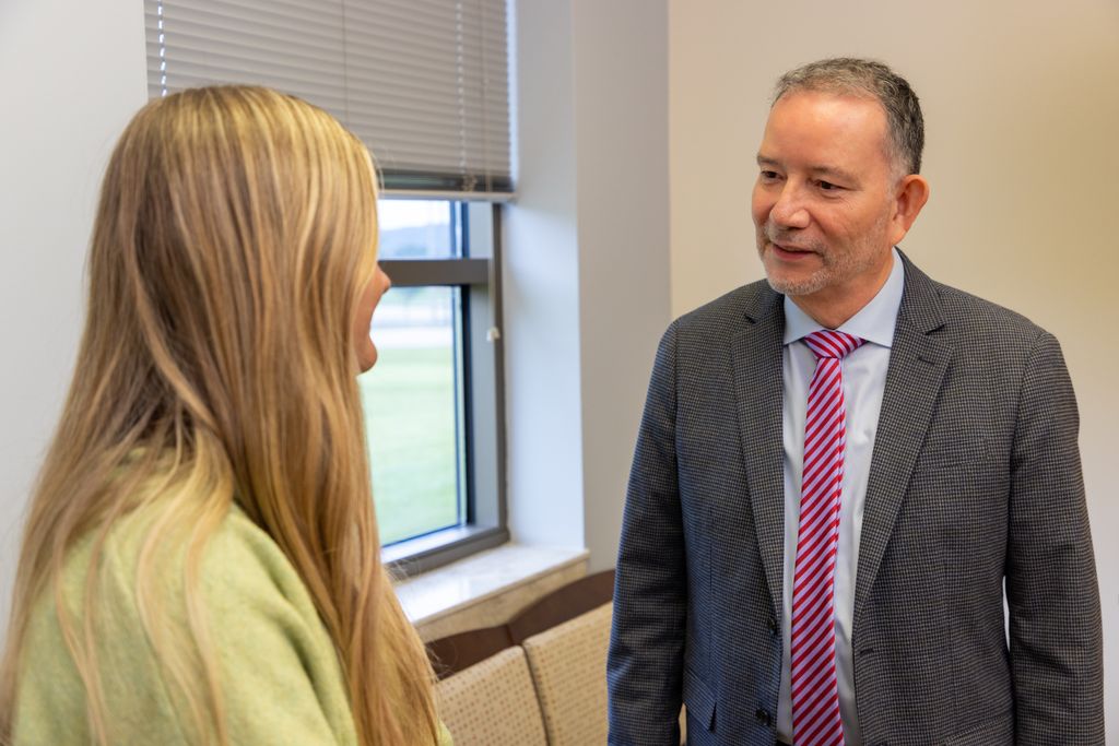 Healthcare administrator in a suit speaking one-on-one with a woman in a private office at Gadsden Cancer Clinic.