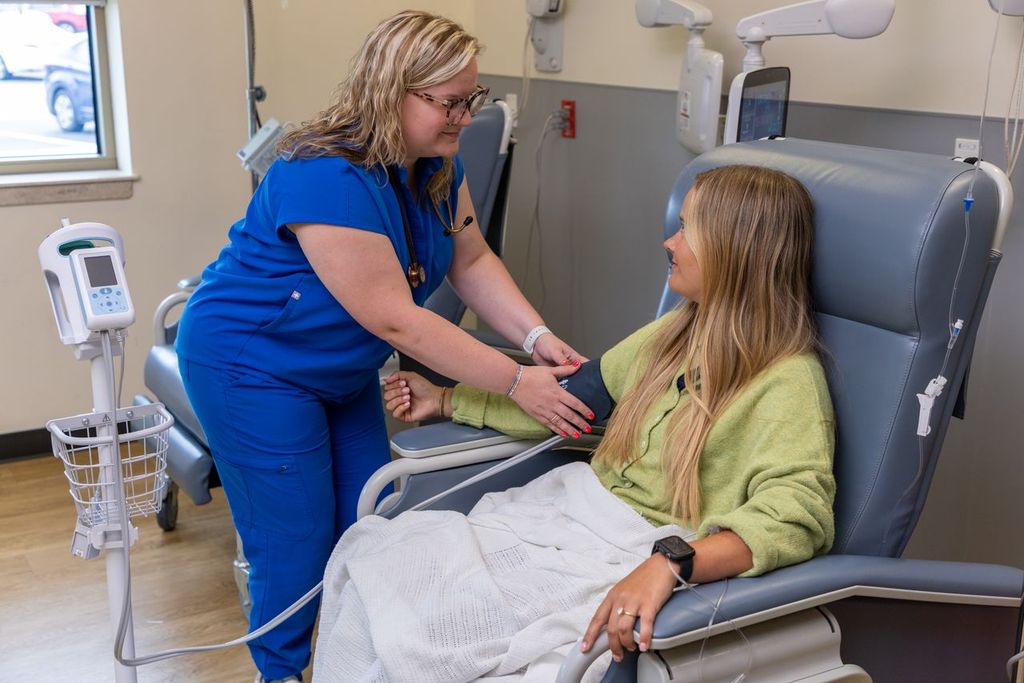Nurse placing a blood pressure cuff on a patient seated in an infusion chair at Gadsden Cancer Clinic.