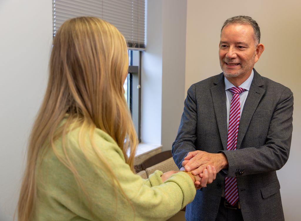 Physician in a suit greeting a patient with a two-handed handshake at Gadsden Cancer Clinic