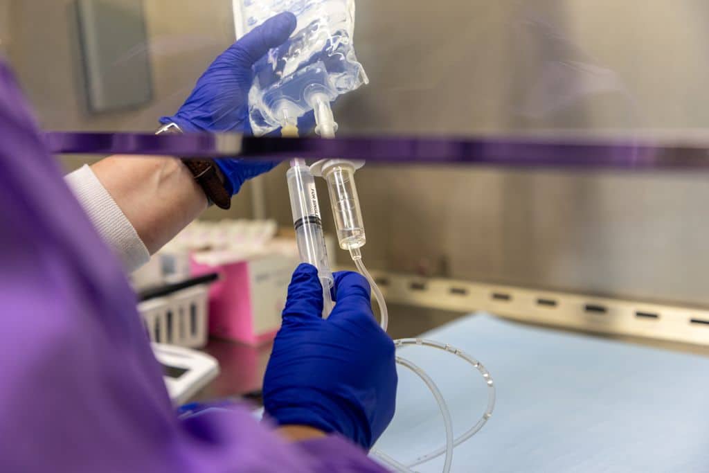 Pharmacy staff compounding IV chemotherapy medication inside a biosafety cabinet at Gadsden Cancer Clinic